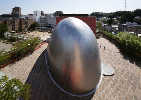 Blob-shaped silver building contrasts with a red tower at Japanese music college