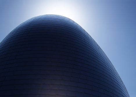 Blob-shaped silver building contrasts with a red tower at Japanese music college