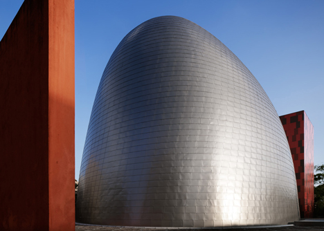 Blob-shaped silver building contrasts with a red tower at Japanese music college