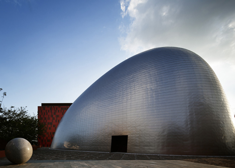 Blob-shaped silver building contrasts with a red tower at Japanese music college