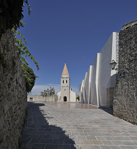 Concrete-clad sports hall by Idis Turato with both faceted and bumpy facades