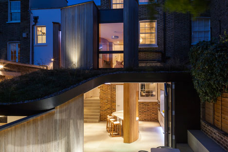 Curvy timber extension by Scott Architects features a sloping grass roof
