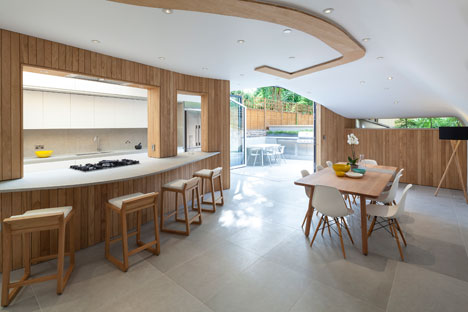 Curvy timber extension by Scott Architects features a sloping grass roof