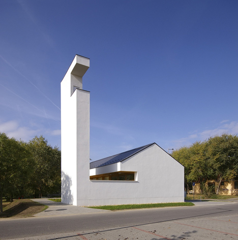 Church congregation hall by SAGRA Architects features a towering white bell tower