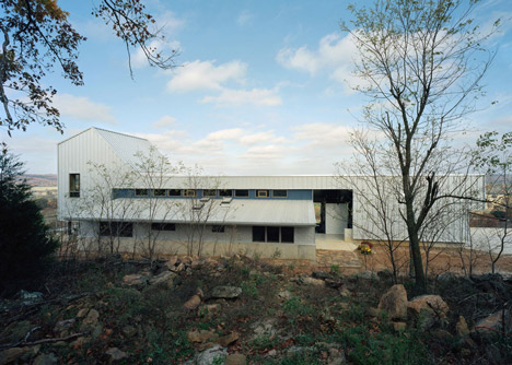 Angular metal roof wraps around a hilltop house by deMx architecture