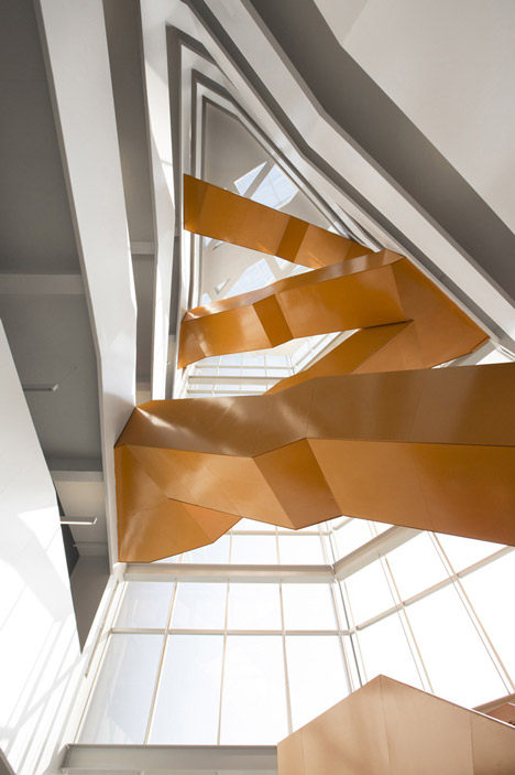 Grand orange staircase ascends through college by Saucier + Perrotte