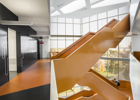 Grand orange staircase ascends through college by Saucier + Perrotte