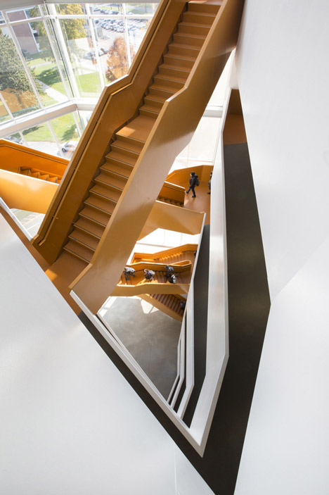 Grand orange staircase ascends through college by Saucier + Perrotte