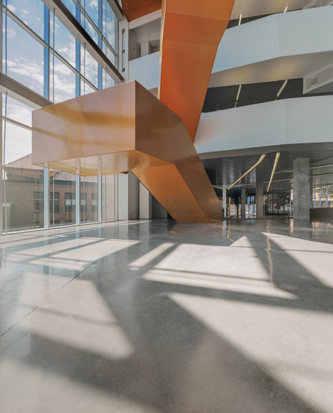 Grand orange staircase ascends through college by Saucier + Perrotte