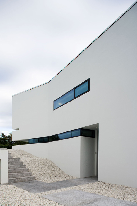 Doorway hidden in volcanic stone wall of B25 house by PK Arkitektar