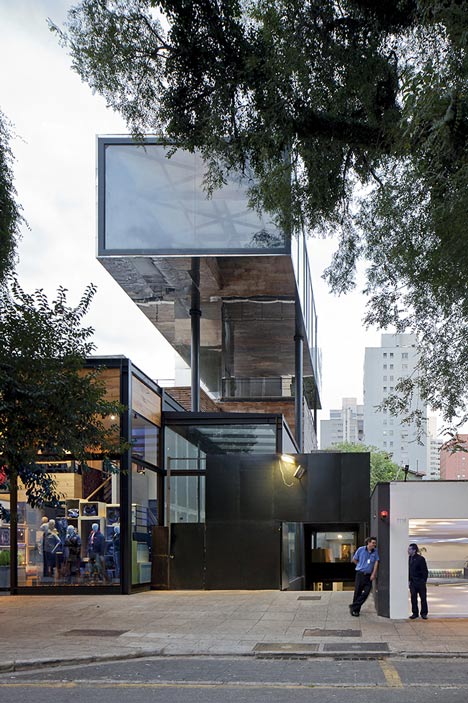 Shiny metal box hovers above shopping and restaurant complex by Triptyque