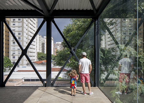 Shiny metal box hovers above shopping and restaurant complex by Triptyque