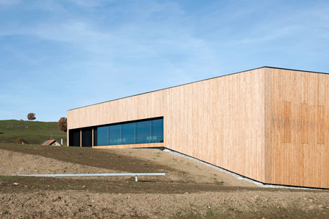 Timber walls feature narrow vertical slices at Virdis Architecture's Lussy Sports Hall