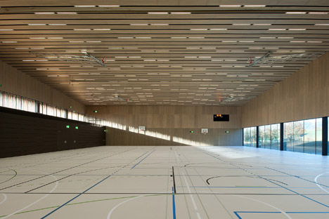 Timber walls feature narrow vertical slices at Virdis Architecture's Lussy Sports Hall