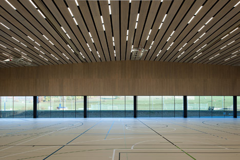 Timber walls feature narrow vertical slices at Virdis Architecture's Lussy Sports Hall