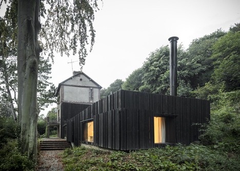 Blackened timber house extension with textured walls by Marchi Architectes
