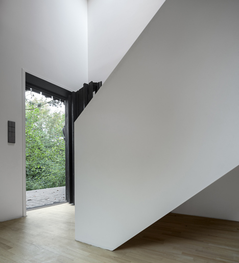Blackened timber house extension with textured walls by Marchi Architectes