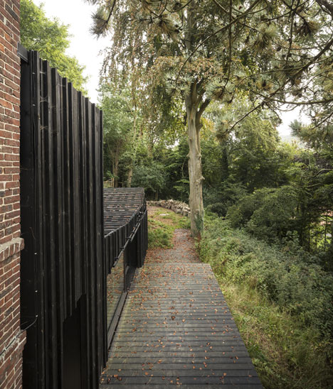 Blackened timber house extension with textured walls by Marchi Architectes
