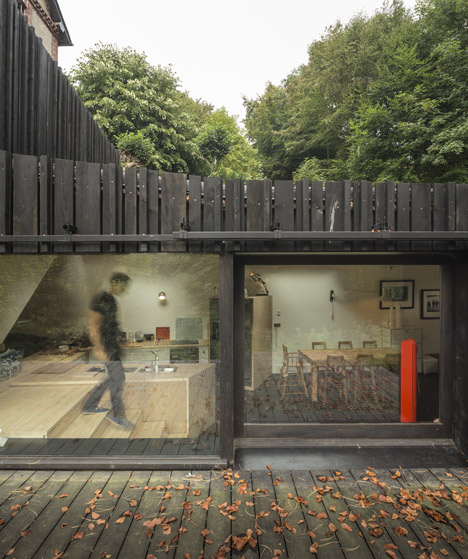 Blackened timber house extension with textured walls by Marchi Architectes