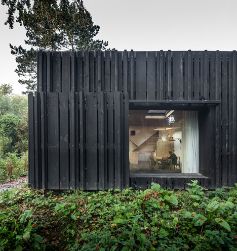 Blackened timber house extension with textured walls by Marchi Architectes