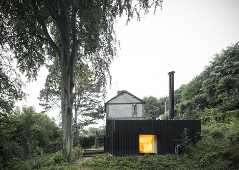 Blackened timber house extension with textured walls by Marchi Architectes
