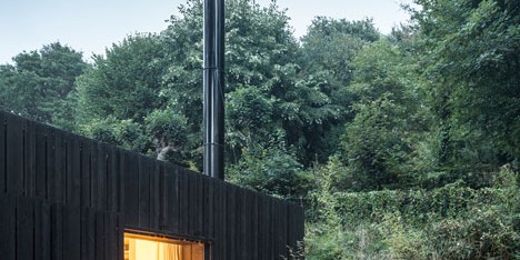 Blackened timber house extension with textured walls by Marchi Architectes