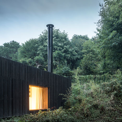 Blackened timber house extension with textured walls by Marchi Architectes