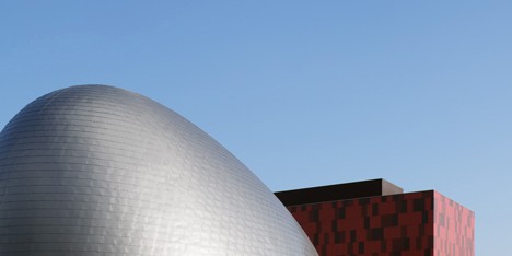 Blob-shaped silver building contrasts with a red tower at Japanese music college