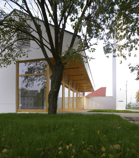 Church congregation hall by SAGRA Architects features a towering white bell tower