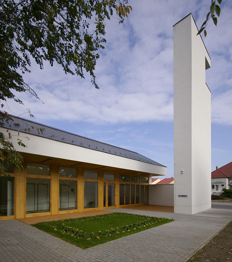 Church congregation hall by SAGRA Architects features a towering white bell tower