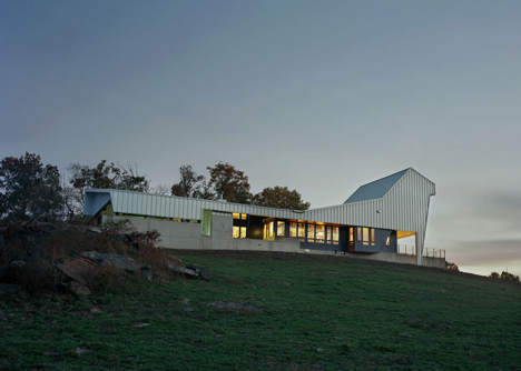 Angular metal roof wraps around a hilltop house by deMx architecture