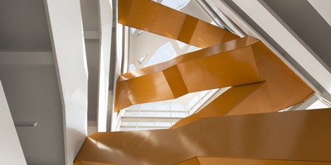 Grand orange staircase ascends through college by Saucier + Perrotte