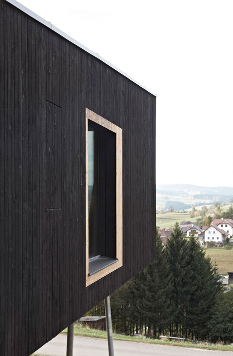 Black-painted S House by Hammerschmid Pachl Seebacher raised up on stilts