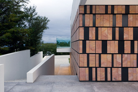 Doorway hidden in volcanic stone wall of B25 house by PK Arkitektar