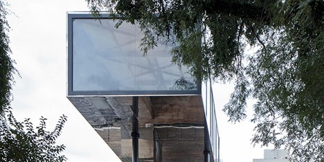Shiny metal box hovers above shopping and restaurant complex by Triptyque