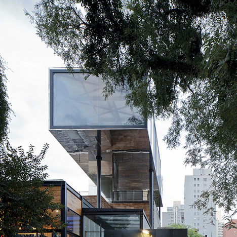 Shiny metal box hovers above shopping and restaurant complex by Triptyque