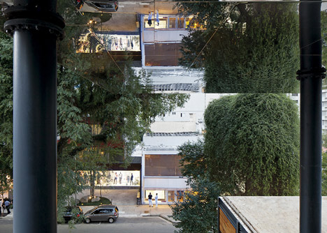 Shiny metal box hovers above shopping and restaurant complex by Triptyque