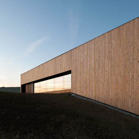 Timber walls feature narrow vertical slices at Virdis Architecture's Lussy Sports Hall