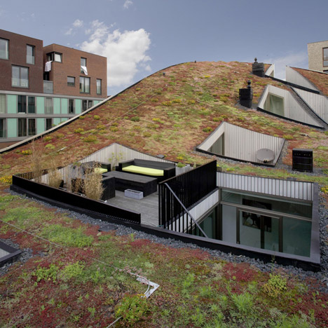 Terraces are cut out of the curved green roof of NL Architects’ Funen Blok K