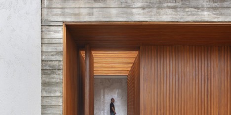 Red wood corridor forms entrance to concrete home in Brazil by Studio Guilherme Torres