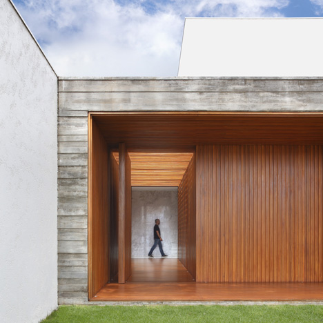 Red wood corridor forms entrance to concrete home in Brazil by Studio Guilherme Torres