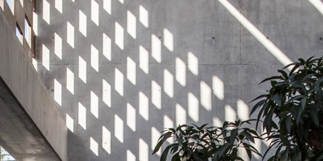 Perforated screens cast graphic shadow patterns over concrete house by Pitsou Kedem
