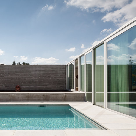 Concrete and glass extension to Belgian house shelters a poolside patio