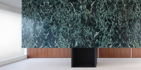 Monolithic marble partition perches on top of a steel fireplace in Antwerp penthouse