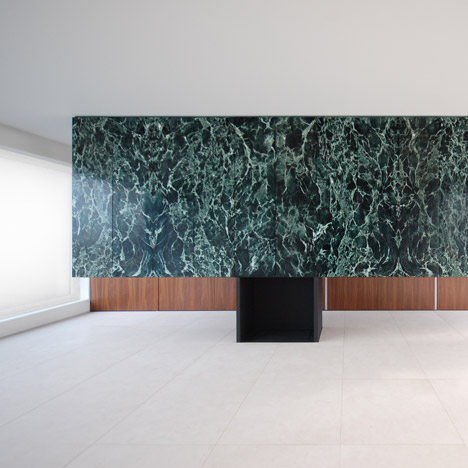Monolithic marble partition perches on top of a steel fireplace in Antwerp penthouse