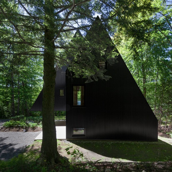Jean Verville creates black fairytale-like cottage in a Quebec forest