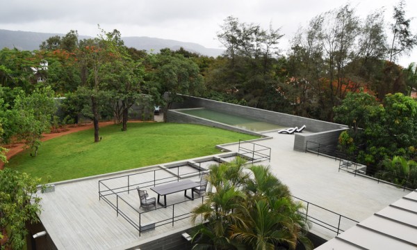 Spasm Architects clad Indian house in local stone and wrap it around a sunken courtyard.