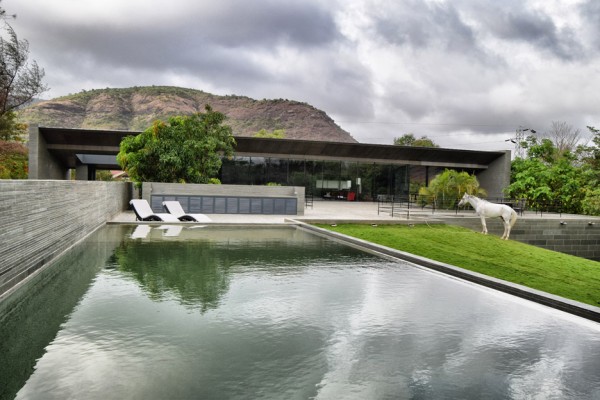 Spasm Architects clad Indian house in local stone and wrap it around a sunken courtyard.