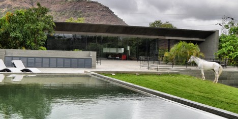 Spasm Architects clad Indian house in local stone and wrap it around a sunken courtyard.