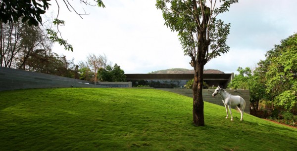 Spasm Architects clad Indian house in local stone and wrap it around a sunken courtyard.